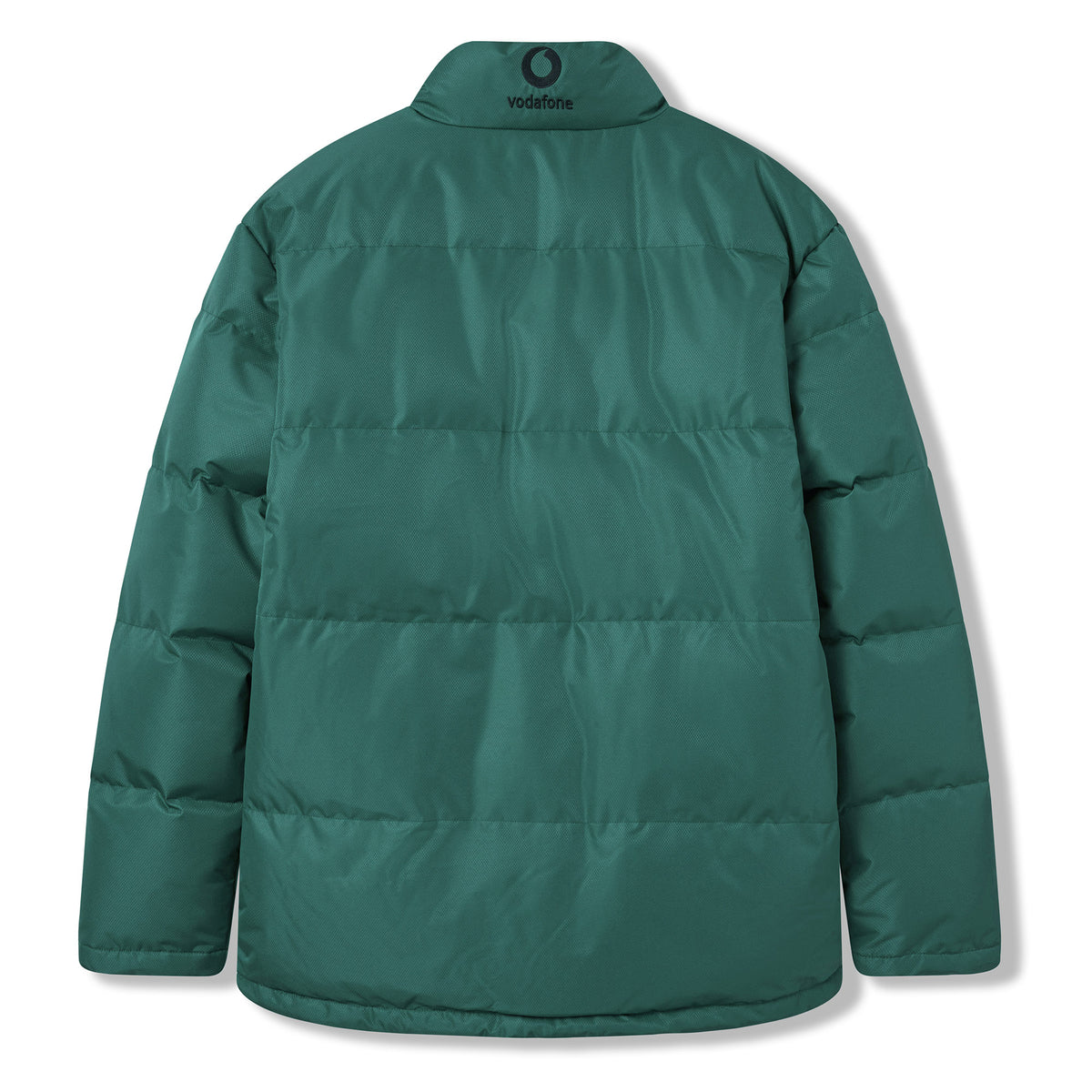The Ireland 26 Puffer Jacket by Canterbury is shown from the back, featuring a high collar and horizontal stitching. Inspired by the classic Ireland Rugby jacket, it displays a small Vodafone logo near the neckline.
