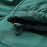 Close-up of green Ireland 26 Puffer Jacket by Canterbury fabric with visible grid pattern, showing a drawstring and plastic toggle featuring a white leaf design.