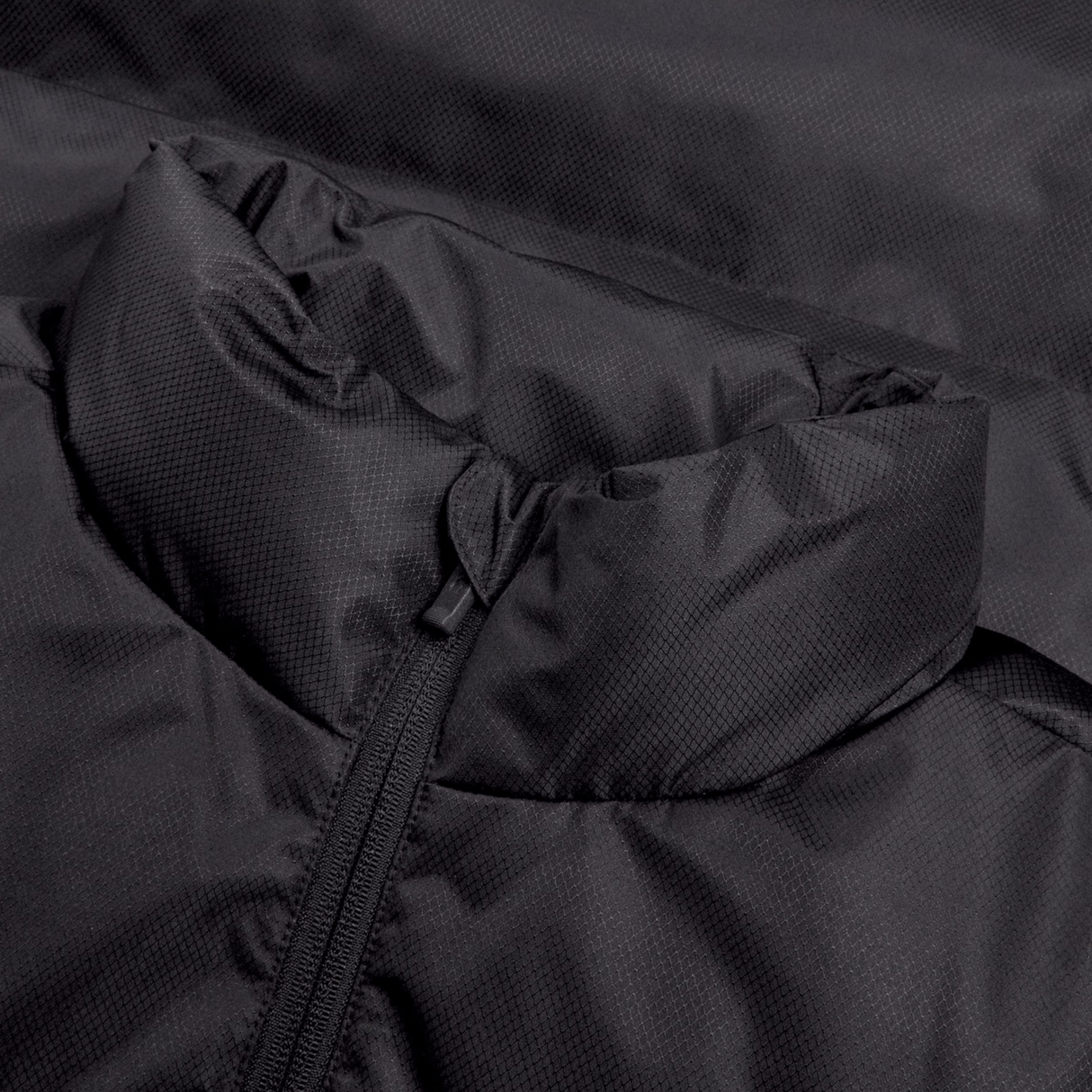 Close-up of the Ireland 24 Padded Gilet by Canterbury, showcasing a high collar with a partially closed zipper and crafted from quilted fabric. This black jacket is enhanced with Thermoreg insulation for extra warmth.