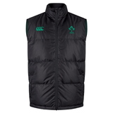 The Ireland 24 Padded Gilet by Canterbury is a sleeveless black puffer vest with Thermoreg insulation, featuring a zip front and adorned with green emblems and logos on the chest.