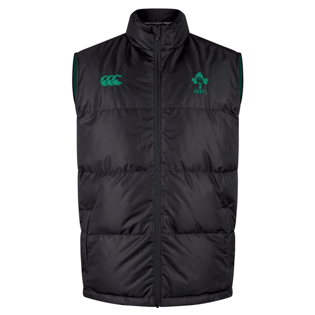 The Ireland 24 Padded Gilet by Canterbury is a sleeveless black puffer vest with Thermoreg insulation, featuring a zip front and adorned with green emblems and logos on the chest.