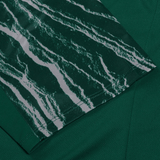 Close-up of the Ireland 24 Superlight Training T-Shirt by Canterbury, showcasing a green fabric with a portion displaying a white and darker green marble-like pattern, made from breathable and quick-drying recycled polyester.