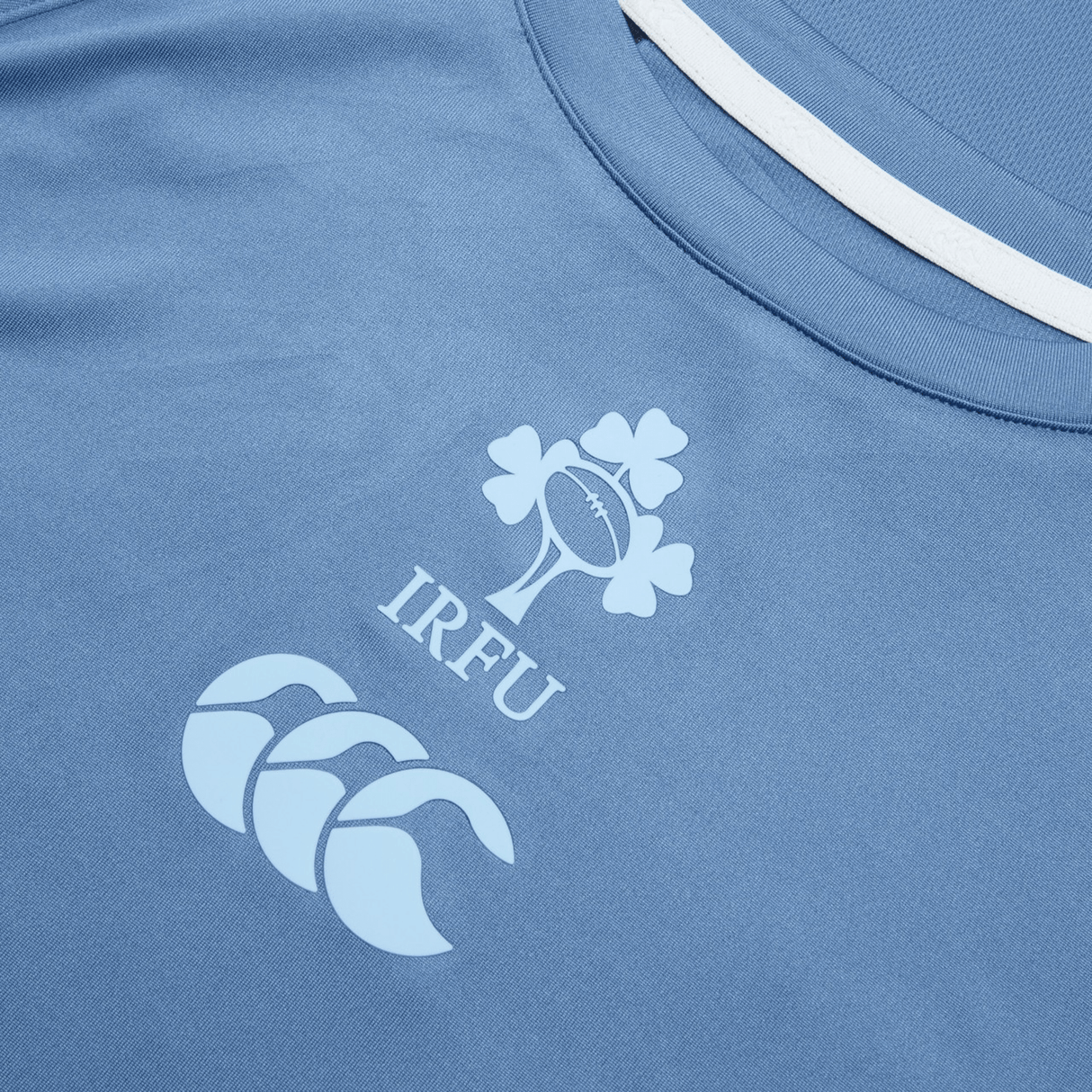Ireland 24 Superlight Training T-Shirt by Canterbury featuring the Irish Rugby Football Union (IRFU) emblem with a shamrock and rugby ball design, along with the Canterbury brand logo below it. Perfect for fans of Ireland's rugby team.