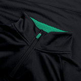 Close-up of the Ireland 1/4 Zip Training Top 24 by Canterbury, showcasing a sleek black exterior with a green inner lining and hexagonal pattern. The zipper is partially open, revealing the vibrant green interior.