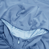 A close-up of the Ireland Training Hoodie 24 by Canterbury reveals a light blue hood with part of the zipper. The polyester fabric boasts a smooth, slightly glossy finish.