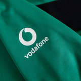 A green fabric from the Ireland 25/26 Training Hoodie by Canterbury featuring the white Vodafone logo, shown beside black ribbed material.