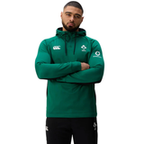 Man wearing the Ireland 25/26 Training Hoodie by Canterbury, featuring the IRFU crest, with arms crossed against a plain white background.