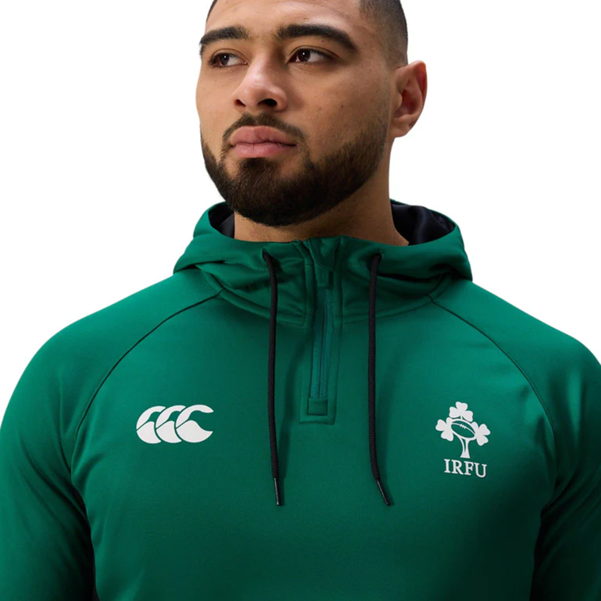 A man wears the official Ireland 25/26 Training Hoodie by Canterbury, a green quarter-zip with the Canterbury logo and IRFU crest—ideal for fans to show their support.