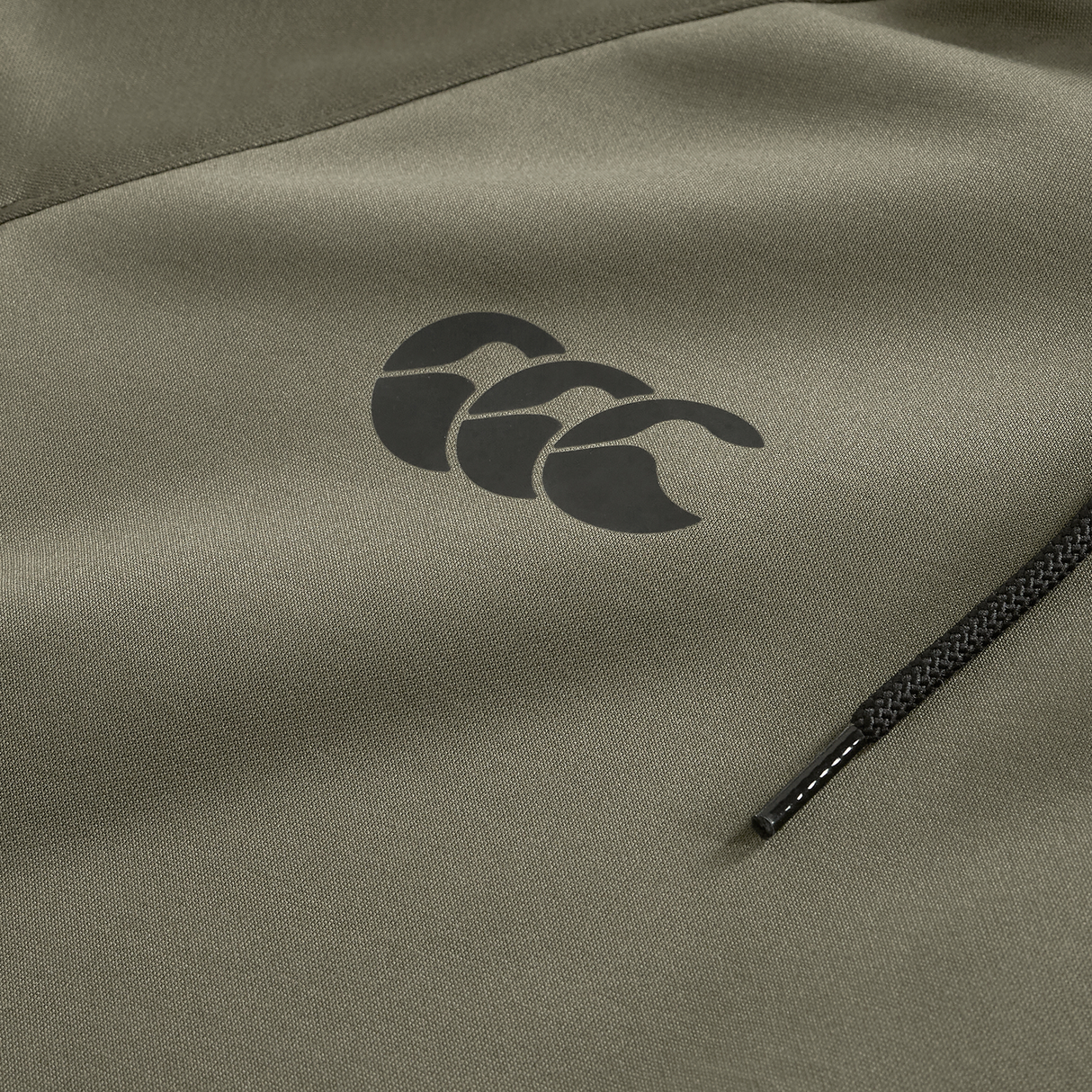 Close-up of the Ireland 25/26 Training Hoodie by Canterbury in olive green, featuring a black triple-wave logo above a horizontal zippered pocket.