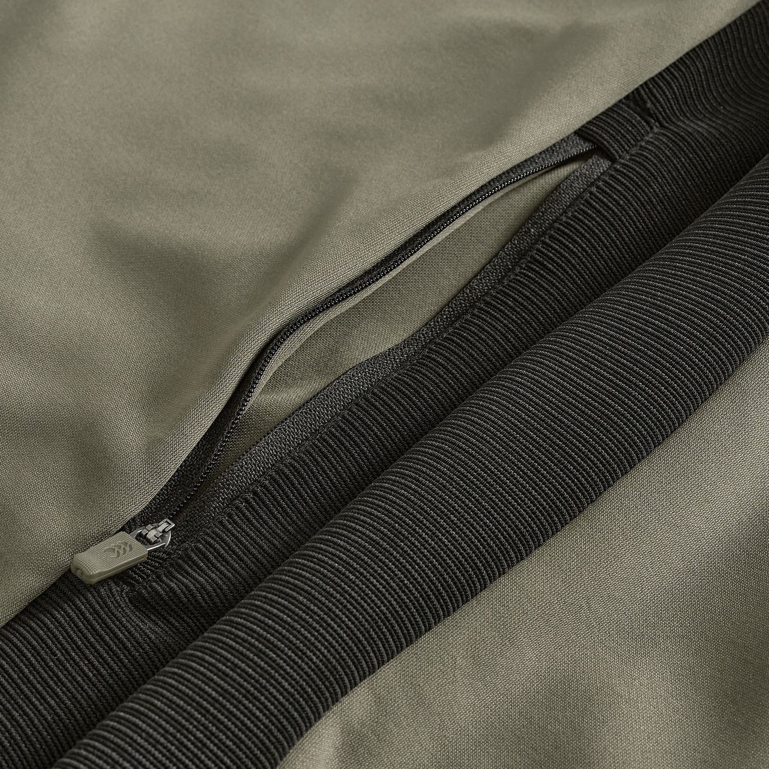 Close-up of the Ireland 25/26 Training Hoodie by Canterbury, featuring a khaki fabric, black ribbed cuff, and open zipper pocket—showcasing signature Canterbury details.