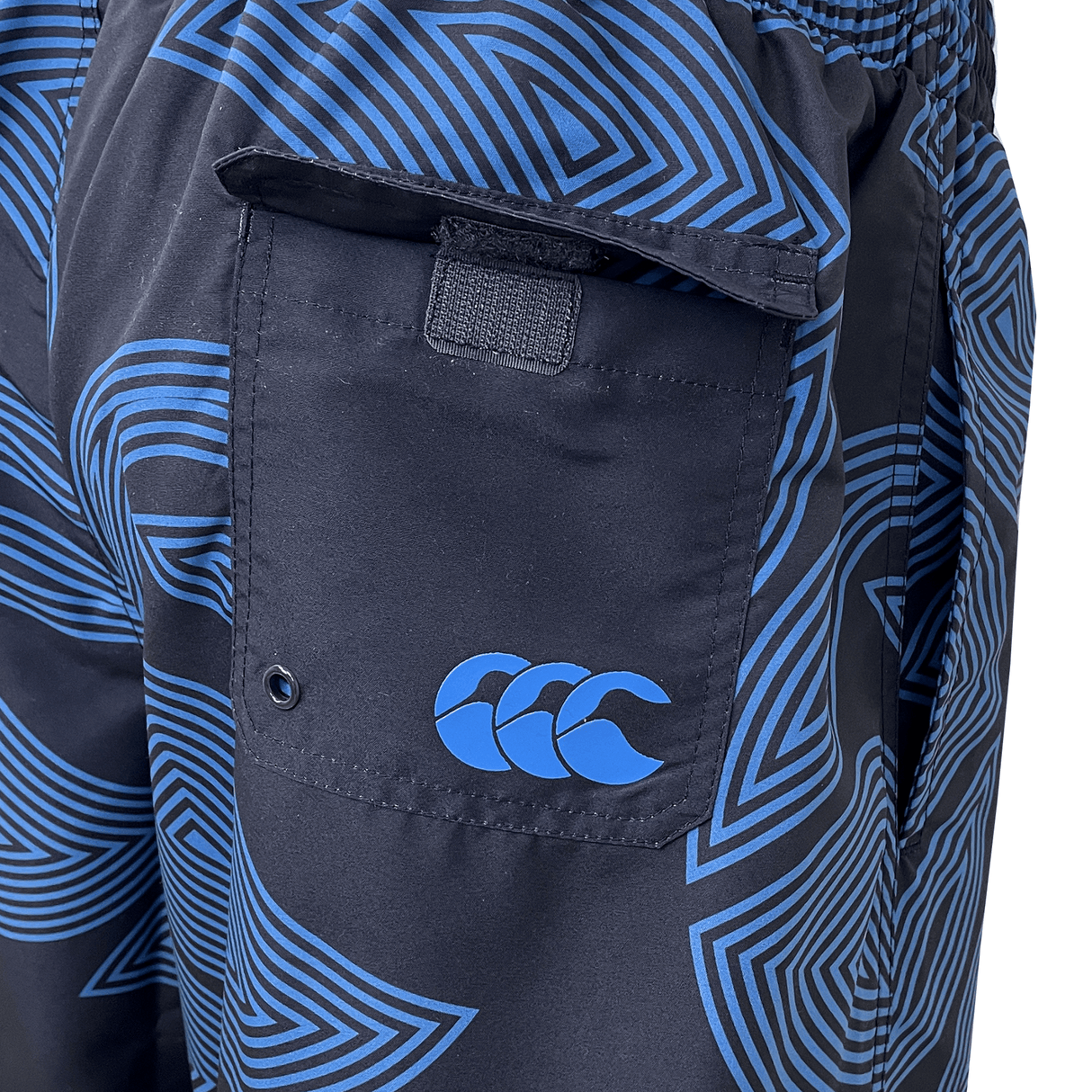 Close-up of the Canterbury Radial Awning 8in Woven Swim Short, showcasing its blue and black pattern with an elasticated waist, Velcro back pocket, and a distinctive three-wave logo.