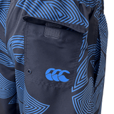 Close-up of the Canterbury Radial Awning 8in Woven Swim Short, showcasing its blue and black pattern with an elasticated waist, Velcro back pocket, and a distinctive three-wave logo.