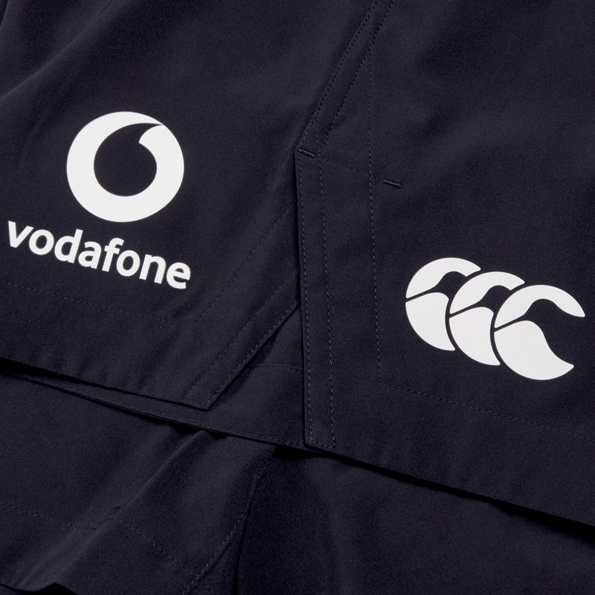 Close-up of the dark-colored Ireland 24 Woven Gym Short by Canterbury featuring white logos of Vodafone and Canterbury.