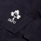 Close-up of a dark fabric with a white Irish Rugby Football Union (IRFU) logo, featuring a shamrock and rugby ball, printed on what appears to be the Ireland 24 Woven Gym Short by Canterbury.