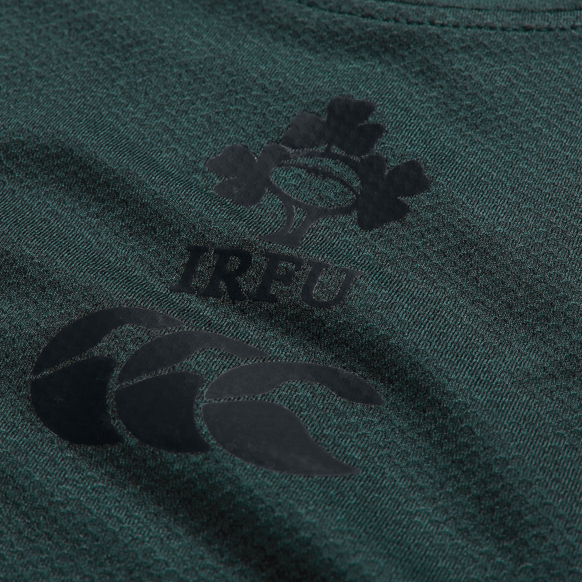 Close-up of the Ireland 26 Elite Training Tee by Canterbury in green, showcasing the IRFU logo with a shamrock and rugby ball motif above the Canterbury brand logo. Crafted from Vapodri breathable sportswear, this elite training shirt is designed to deliver comfort and performance both on and off the field.