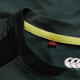 Close-up of the collar on the Canterbury Ireland 26 Elite Training Tee in dark green, featuring yellow trim and prominent white and red Canterbury logos inside and out, highlighting Vapodri breathable technology for optimal comfort.