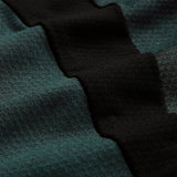 Close-up of textured fabric with alternating dark green and black wavy stripes. The surface reveals intricate knit patterns and a soft finish, showcasing Canterbury’s advanced Vapodri breathable sportswear technology found in the Ireland 26 Elite Training Tee.