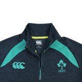 The Ireland 26/27 Summer Tour Elite First Layer by Canterbury is a dark grey lightweight quarter-zip with teal accents, IRFU shamrock and Canterbury logos, and Vapodri tech for comfort—part of the Elite range.