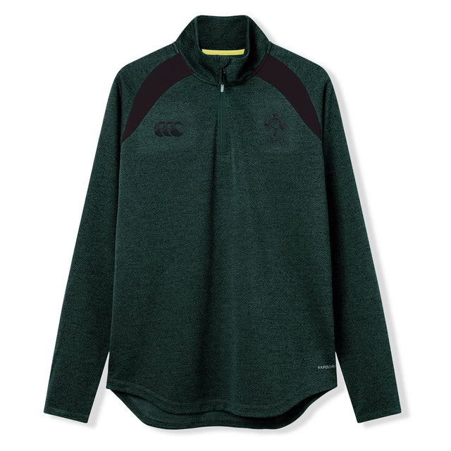 The Ireland 26 Elite First Layer by Canterbury is a dark green, long-sleeve quarter-zip pullover featuring black shoulder accents and chest logos. Crafted from Vapodri fabric for superior moisture management, this top is part of the Canterbury Elite collection and is shown here on a white background.