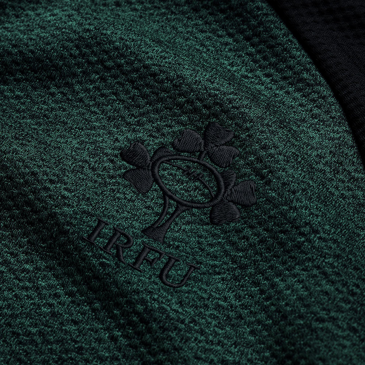 Close-up of the green textured Ireland 26 Elite First Layer by Canterbury, featuring the black embroidered Irish Rugby Football Union (IRFU) shamrock logo and crafted with Canterbury’s Elite Vapodri technology for enhanced comfort.