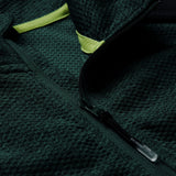 Close-up of the Ireland 26 Elite First Layer by Canterbury, a textured dark green fleece jacket inspired by an Ireland Rugby training top, featuring a partially opened black zipper and a yellow fabric accent near the collar.