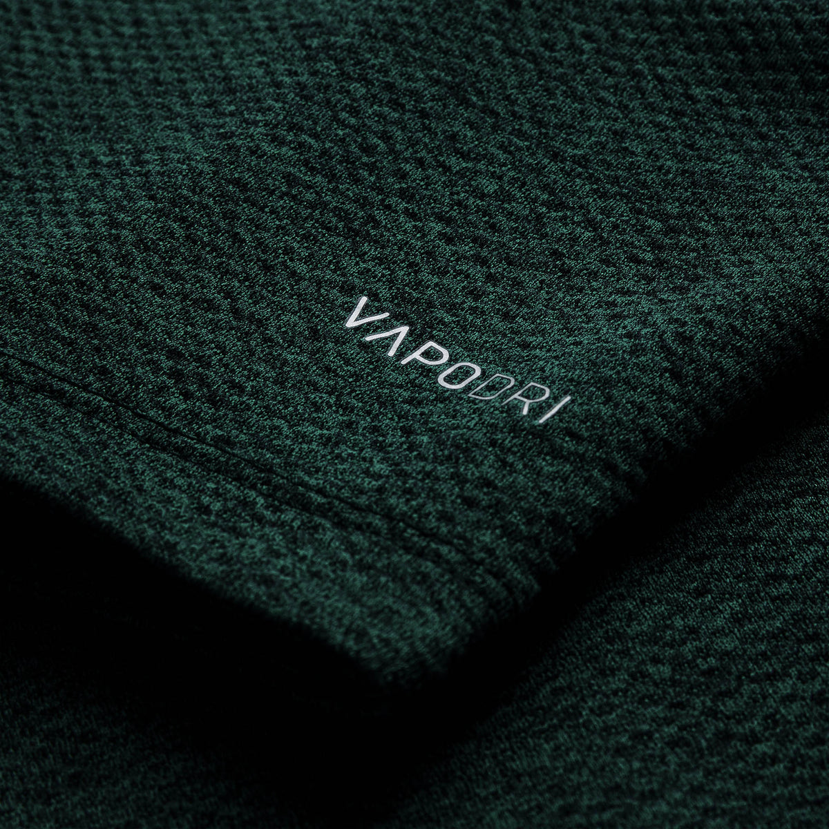 Close-up of dark green textured fabric from the Ireland 26 Elite First Layer by Canterbury, featuring the word “VAPODRI” printed in white text.