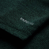 Close-up of dark green textured fabric from the Ireland 26 Elite First Layer by Canterbury, featuring the word “VAPODRI” printed in white text.