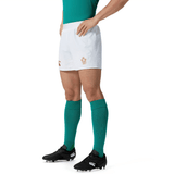 A person dressed in a Canterbury green sports jersey, Ireland 150th Anniversary Home Match Short white shorts, green socks, and black cleats stands confidently with hands on hips, ready to celebrate Ireland's 150th Anniversary.