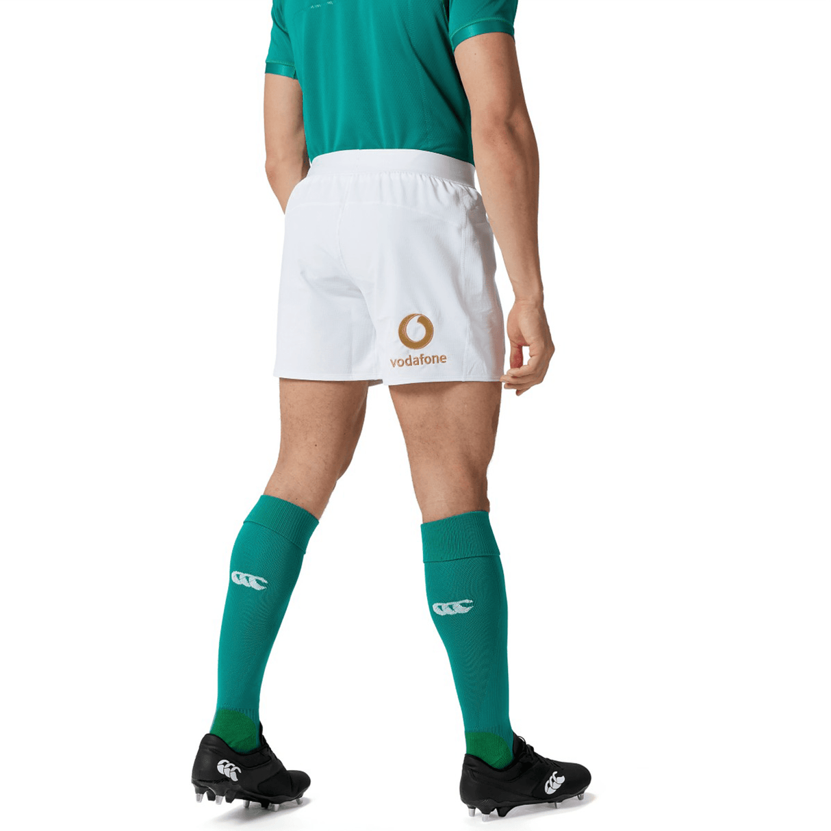 A person is wearing a green sports jersey, Ireland 150th Anniversary Home Match Short by Canterbury featuring the "Vodafone" logo, and green socks, reminiscent of Ireland's 150th Anniversary home match attire, viewed from behind.