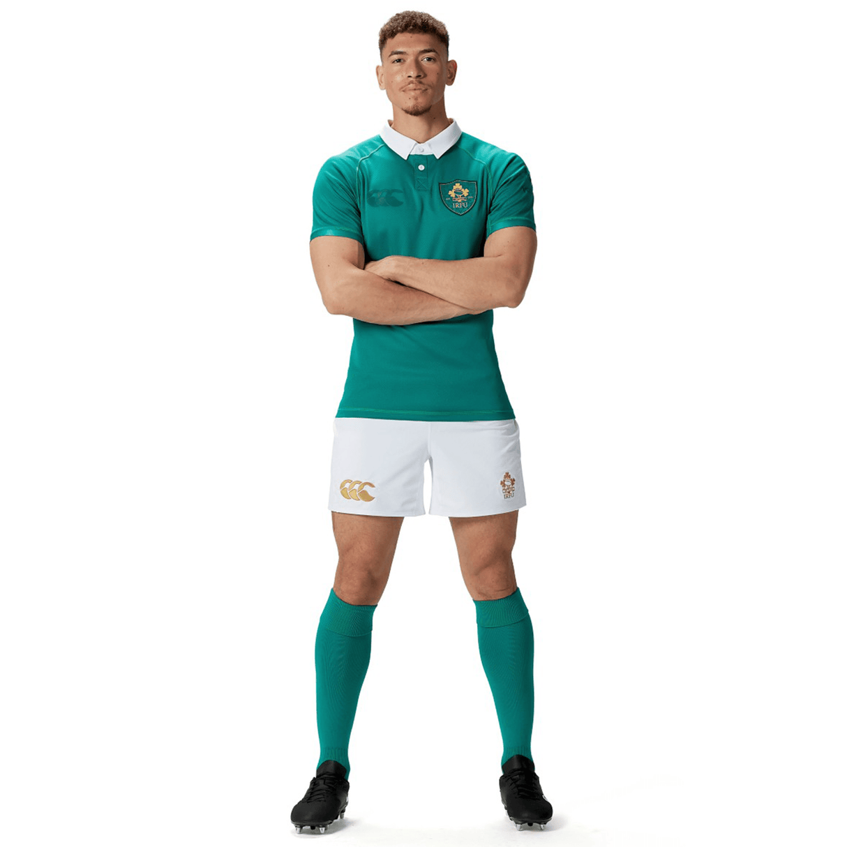 Dressed in the Canterbury Ireland 150th Anniversary Home Match Shorts and top, a man stands with arms crossed, proudly showing off his green rugby uniform complete with green socks and black shoes, all set for the home match against a pristine white background.