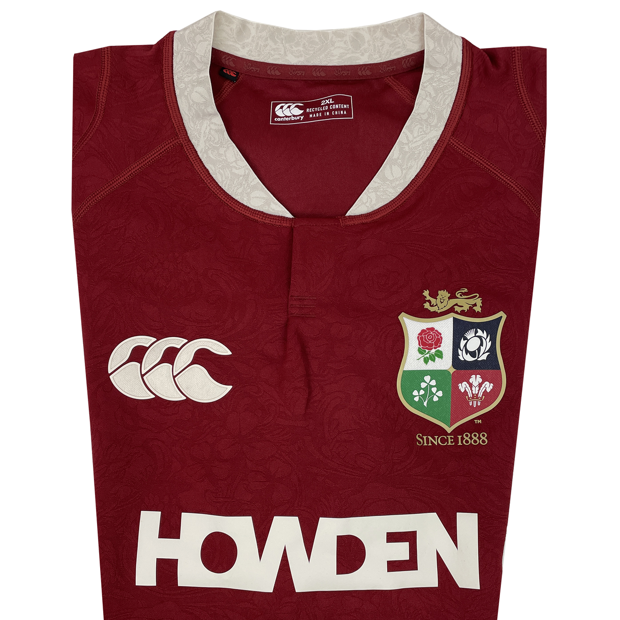 The British & Irish Lions 2025 Players Authentic Jersey by Canterbury showcases a red design with a white collar, Lions emblem, and Canterbury logo alongside "HOWDEN" text. It features intricate patterns and "Since 1888" text, honoring its legacy—ideal for the 2025 tour.