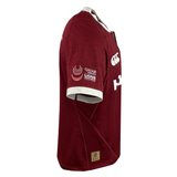 The side view of this red sports jersey, with white collar and sleeve accents, showcases logos on the sleeve and chest. Designed by Canterbury, it mirrors the dynamic style of a British & Irish Lions jersey for their 2025 tour.