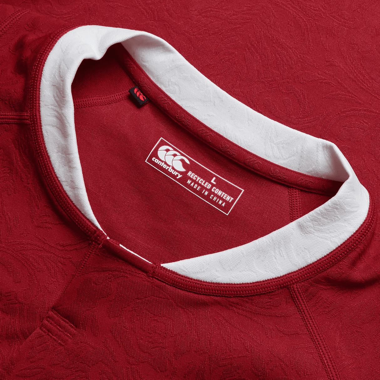 Close-up of a red British & Irish Lions 2025 Players Jersey by Canterbury sports shirt, featuring a white collar and clearly visible label. It emphasizes the moisture-wicking fabric crafted in China from recycled materials, offering optimal comfort and style both on and off the field.