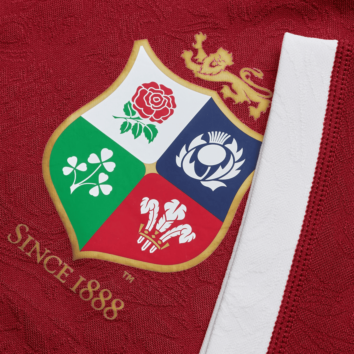 Close-up of the British & Irish Lions 2025 Players Jersey by Canterbury, showcasing the logo with four emblems: a red rose, shamrock, thistle, and feathers beneath a golden lion. The text "SINCE 1888" is visible on this moisture-wicking fabric.