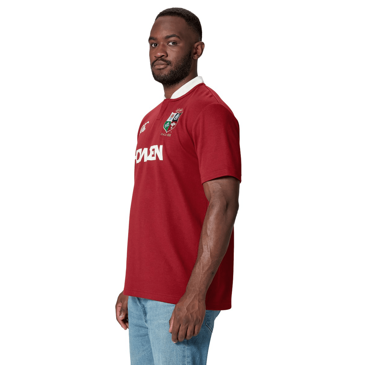 A person wearing the British & Irish Lions 2025 Classic Jersey by Canterbury, featuring white text and a crest on the chest, stands sideways against a stark white background.