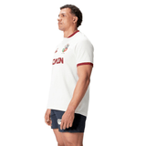 A man wearing the British & Irish Lions 2025 Training Jersey by Canterbury, made from recycled polyester, pairs it with navy shorts as he stands sideways, looking ahead.