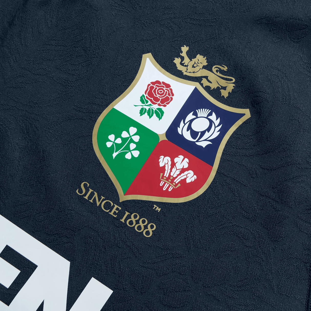 The British & Irish Lions 2025 Training Jersey by Canterbury is a replica training jersey made from recycled polyester, featuring a shield with four symbols—a rose, thistle, shamrock, and three feathers—with "Since 1888" proudly displayed beneath it.