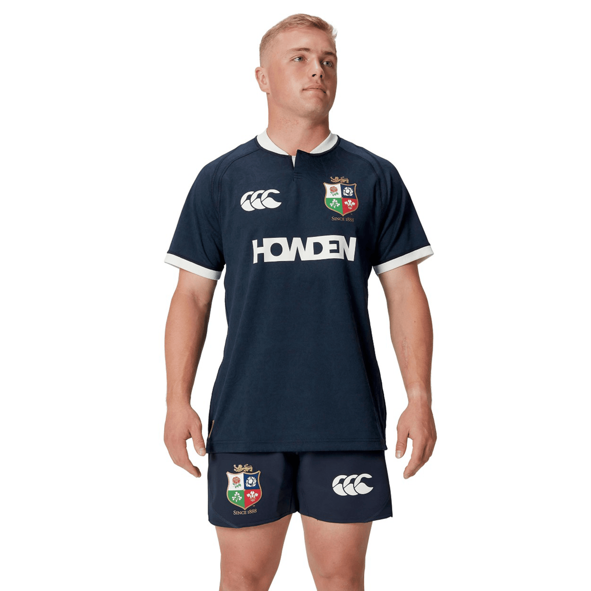 A person wearing a navy athletic outfit, featuring the British & Irish Lions logo on the replica 2025 training jersey and shorts by Canterbury.