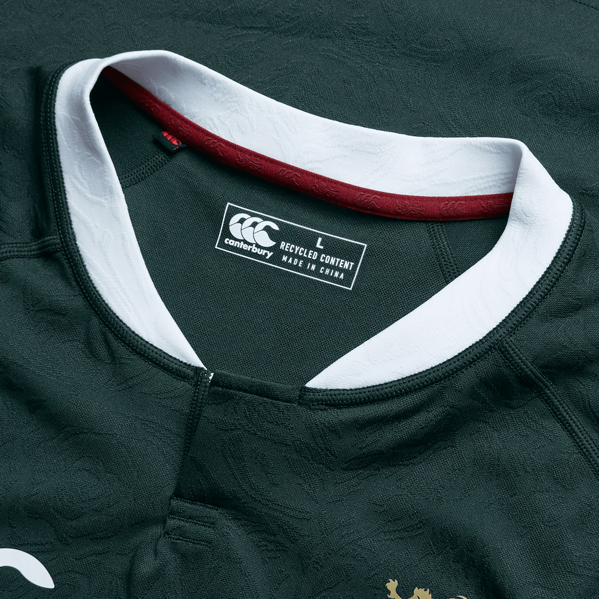 The British & Irish Lions 2025 Training Jersey by Canterbury is a dark green replica jersey with white and maroon accents. It features a Canterbury label specifying size L and "Made in China from Recycled Polyester," making it an ideal choice for eco-conscious fans.