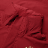 Close-up of the British & Irish Lions 2025 Waterproof Jacket by Canterbury in red, showcasing its adjustable hood and a partially visible gold emblem on the lower right.