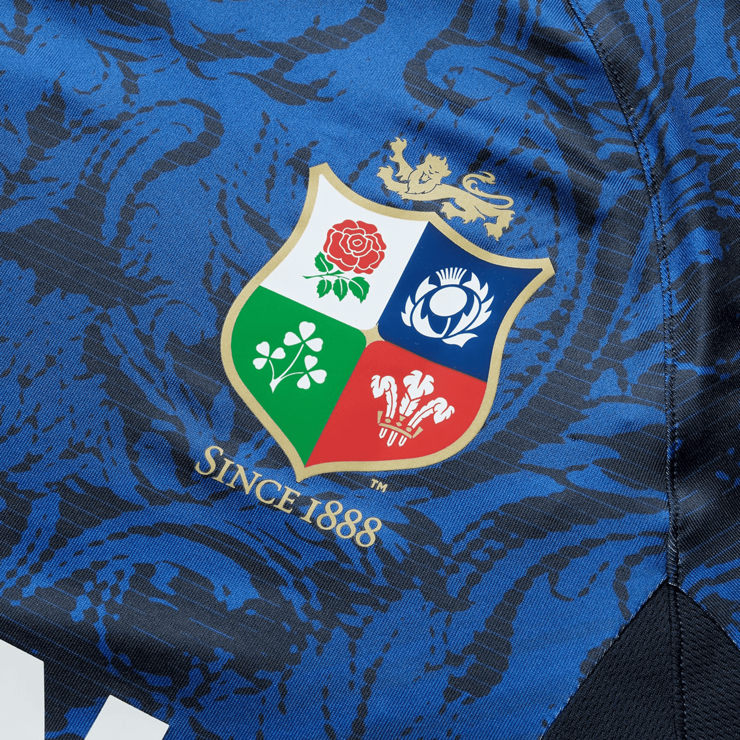 Close-up of the British & Irish Lions 25 Superlight Training Tee by Canterbury in blue, highlighting its detailed texture. The tee features a multicolored shield logo adorned with floral and lion motifs, representing the British & Irish Lions, along with the statement "Since 1888" located below.