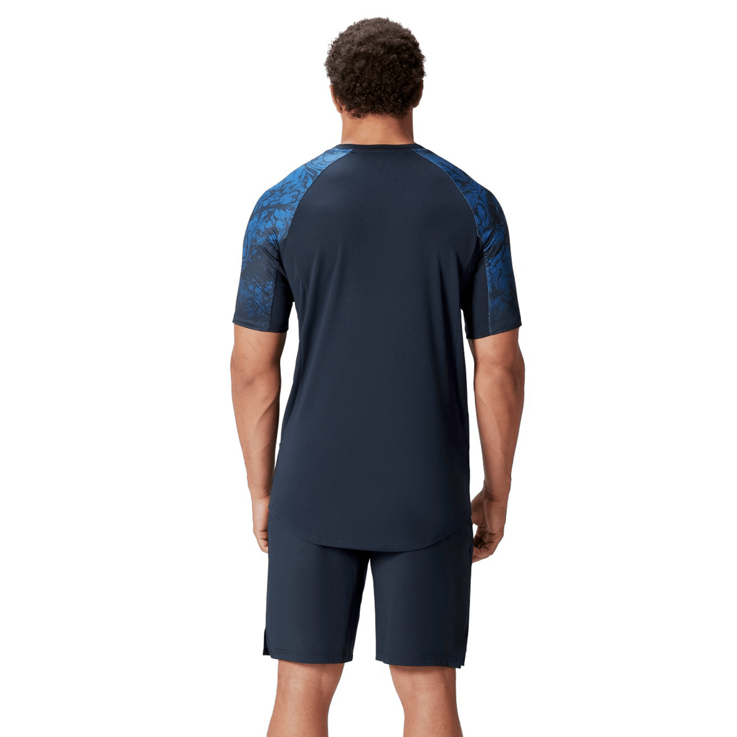 The individual is seen from the back wearing a navy British & Irish Lions 25 Superlight Training Tee by Canterbury, featuring short sleeves and patterned shoulders.