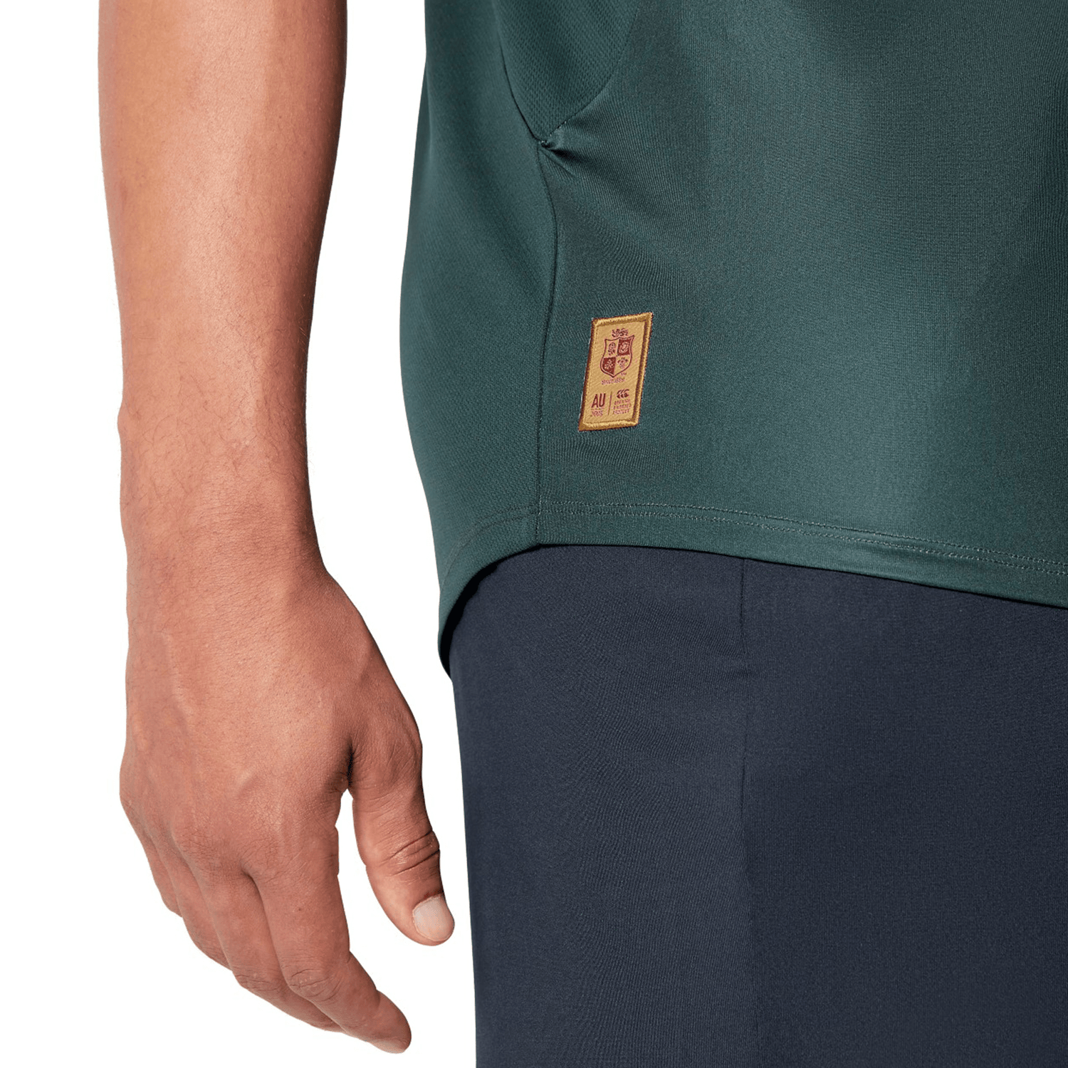 A person wearing a British & Irish Lions 25 Superlight Training Tee by Canterbury in green, which features a small logo on the side, paired with dark pants.