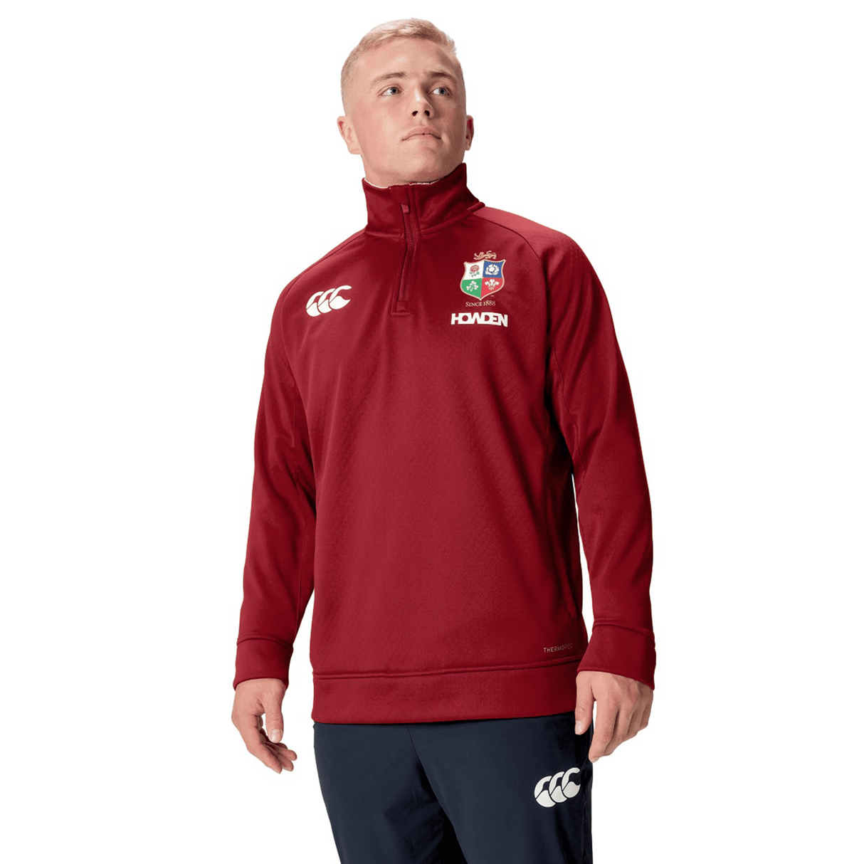 A person wearing the British & Irish Lions 2025 1/4 Zip Fleece by Canterbury stands against a white background, embodying the iconic style of the British & Irish Lions.