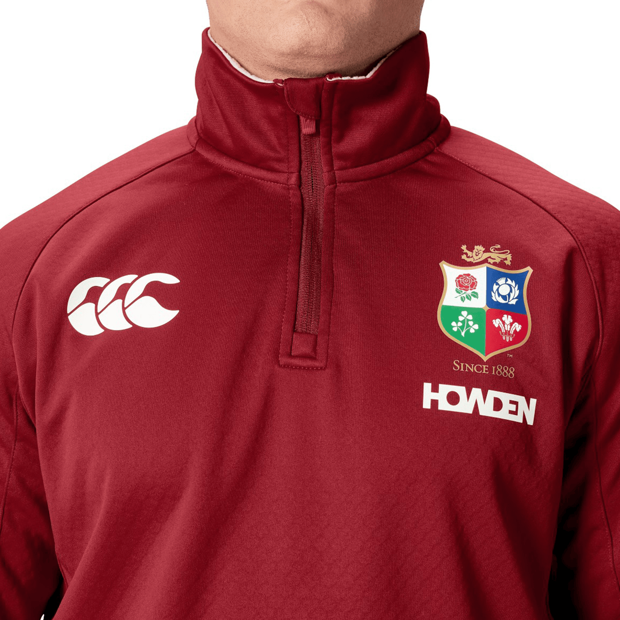 Close-up of a person wearing a maroon British & Irish Lions 2025 1/4 Zip Fleece featuring the iconic crest and "Howden" logo, designed by Canterbury.