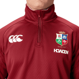 Close-up of a person wearing a maroon British & Irish Lions 2025 1/4 Zip Fleece featuring the iconic crest and "Howden" logo, designed by Canterbury.
