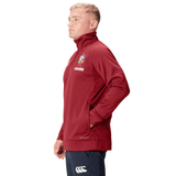 A person in the British & Irish Lions 2025 1/4 Zip Fleece by Canterbury stands sideways with hands in pockets, proudly showcasing their affiliation with the British & Irish Lions.