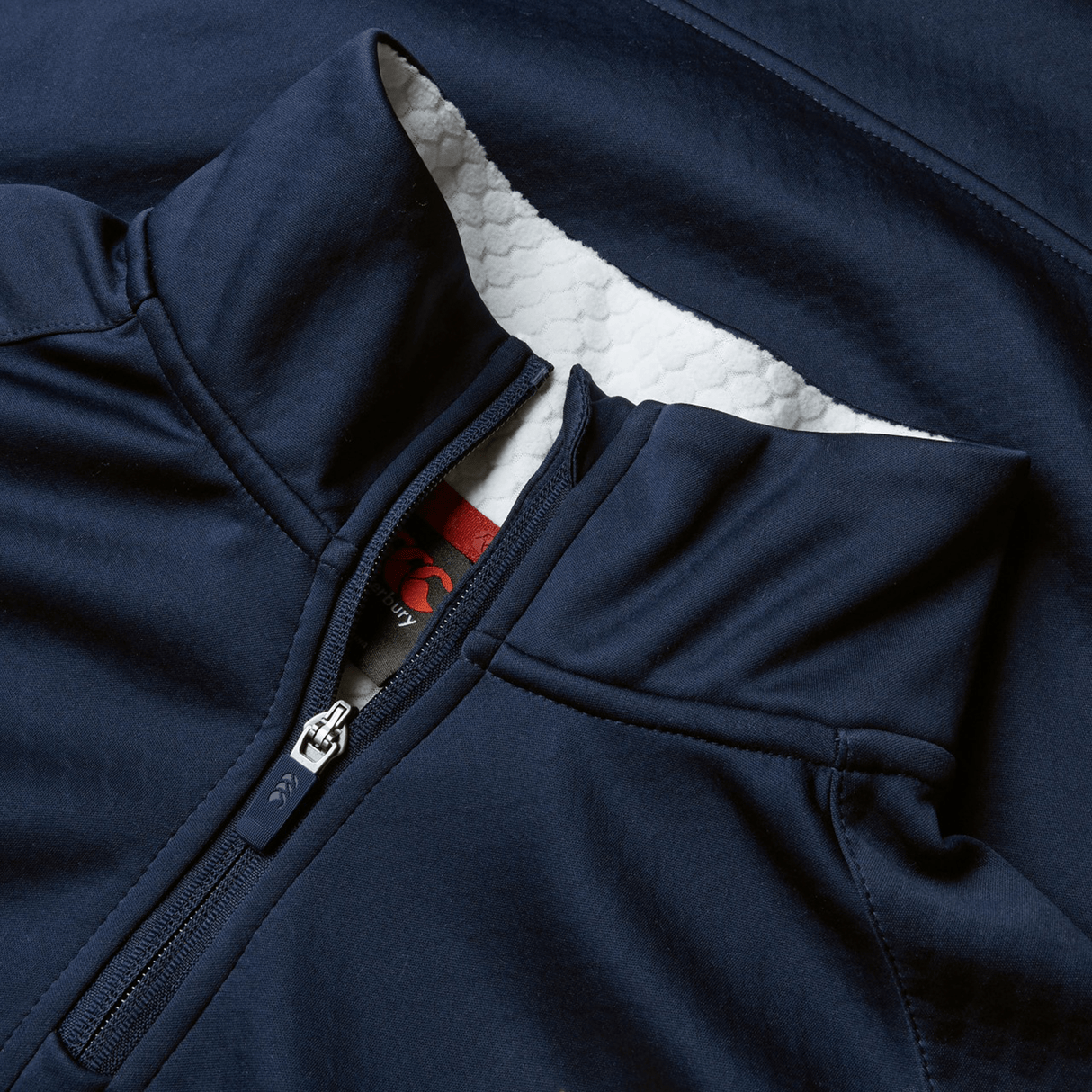 Close-up of the British & Irish Lions 2025 1/4 Zip Fleece by Canterbury, a navy blue jacket featuring a folded collar with a white textured lining beneath, perfect for fans.