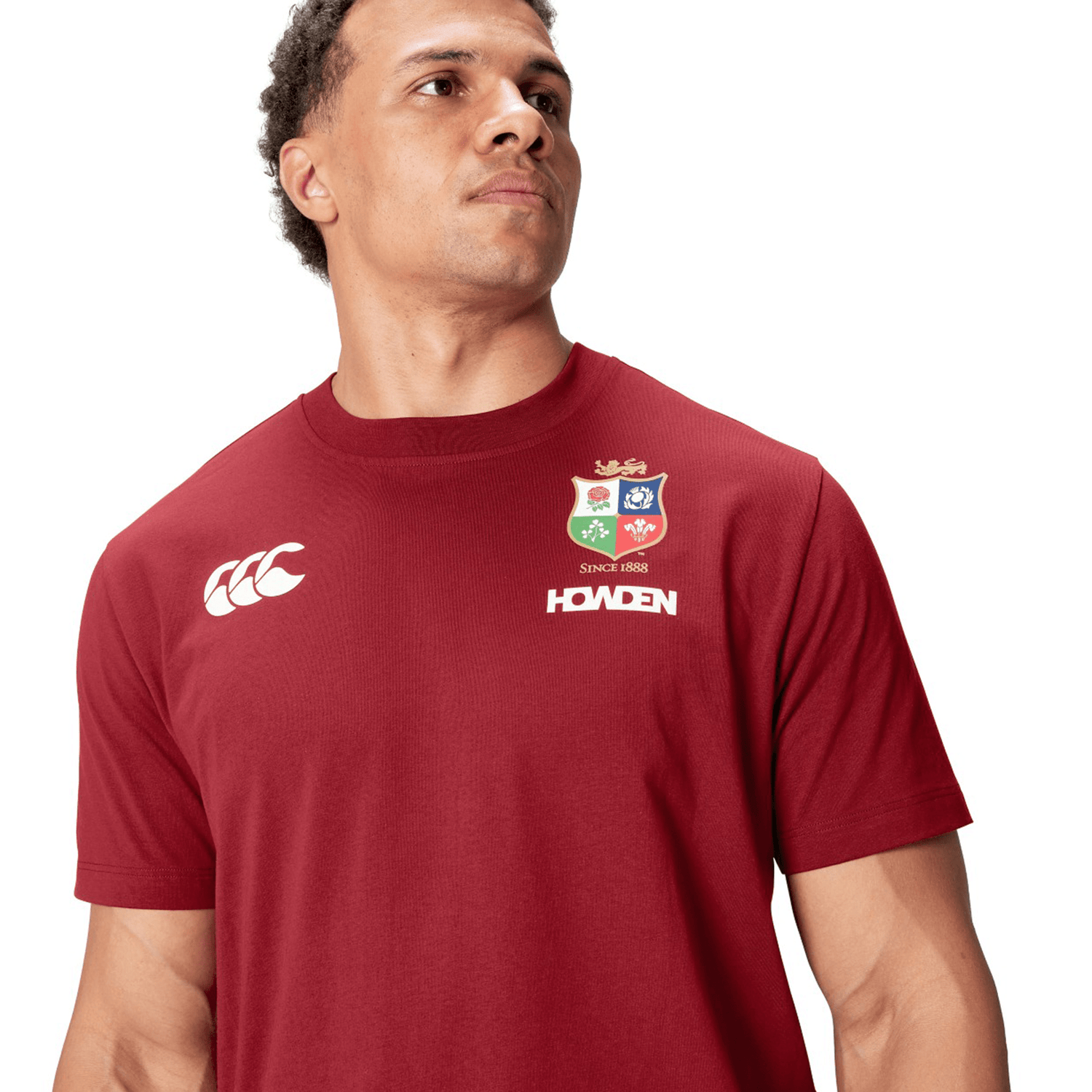 A rugby supporter proudly wears a red British & Irish Lions 2025 Cotton Jersey Tee by Canterbury, featuring the logo and text that perfectly capture his passion for the game.