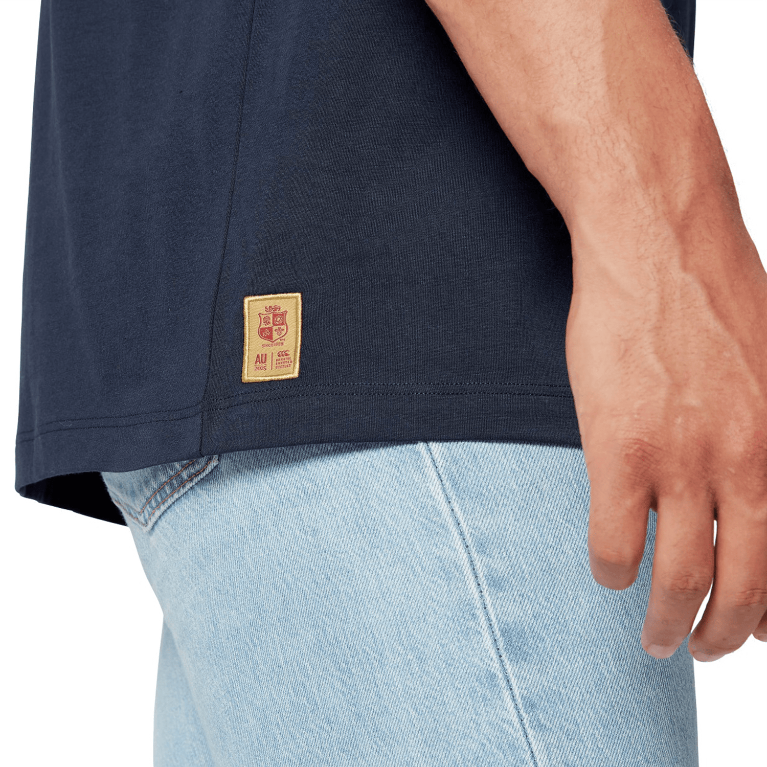 A close-up of a rugby supporter wearing the British & Irish Lions 2025 Cotton Jersey Tee by Canterbury paired with light blue jeans, embodying the spirit of the team.